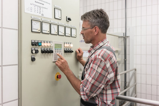 Engineer pressing button of control console in wastewater treatment plant