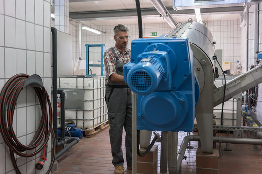 Technician maintaining sewage sludgy dryer in machine room of wastewater treatment plant