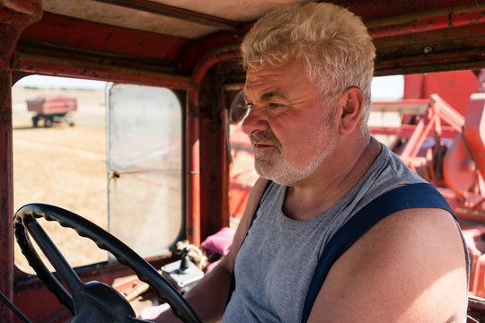 Farmer steering tractor during harvest in drivers cabin