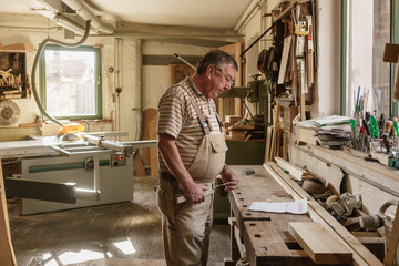 Craftsman in his wood workshop holding  folding rule and studyin