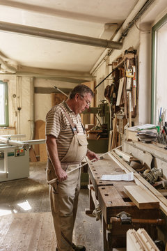 Craftsman in his wood workshop holding  folding rule and studyin