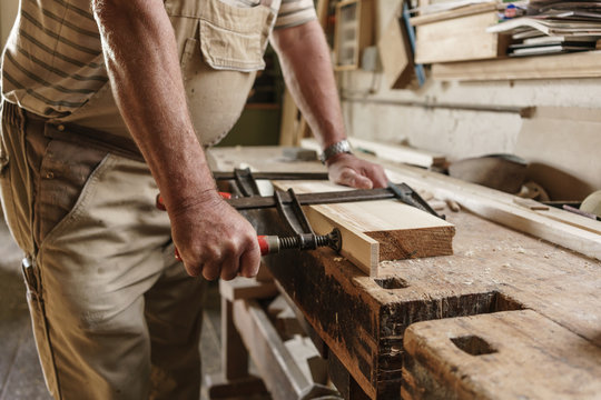 Craftsman in his carpentry workshop pressing wooden workpiece wi