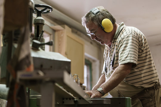 Carpenter in his wood workshop working concentrated at circular saw