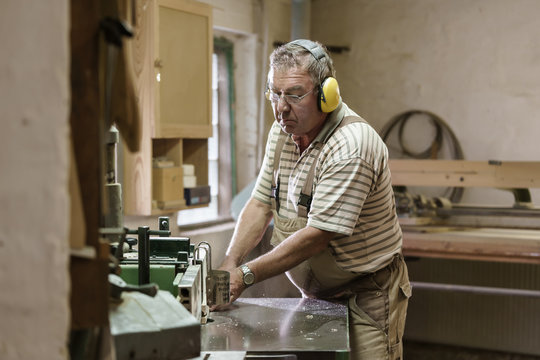 Carpenter in his wood workshop working concentrated at circular saw