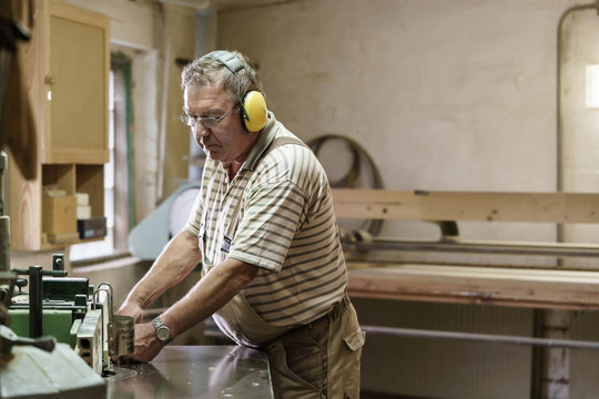 Carpenter in his wood workshop working concentrated at circular saw