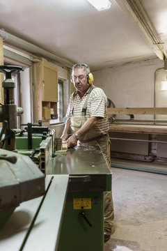 Carpenter in his wood workshop working concentrated at circular saw