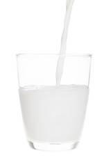 Pouring milk in clear glass isolated on white background with cl