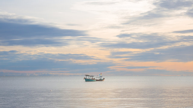 fishing boat floating  in a sea with sunrise