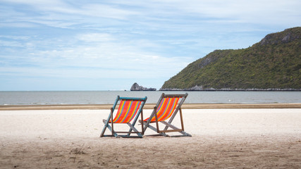 Fototapeta na wymiar rainbow summer two beach chairs for relax on the beach in vacation time