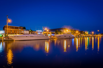 Fototapeta na wymiar Buildings and boats along the waterfront at night, in Annapolis,