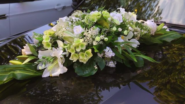 Close up of black car festively decorated with white flowers for wedding cortege.