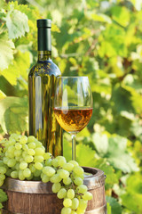 Fototapeta na wymiar Wine in glass with bunch of grape on wooden barrel