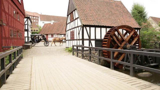 Old town in Aarhus Denmark: Old bridge and watermill with horse carriage passing by in the back ground