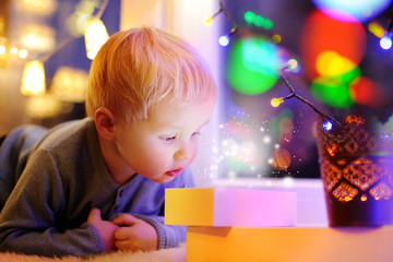 Cute little boy looking on a magical Christmas or New Year gift