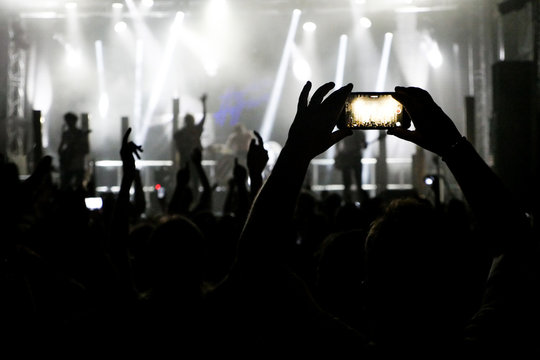 Silhouette of hands recording videos at music concert