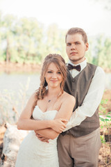 bride and groom standing arm in  against the background grass  lakes