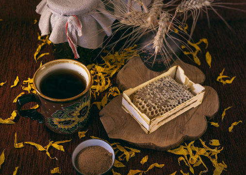 Рамка с сотами меда, пиала с корицей, чашка чая, банки варенья, колосья пшеницы в вазе