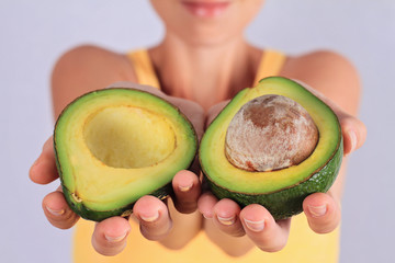 Woman holding avocado closeup. Healthy eating and skin care concept