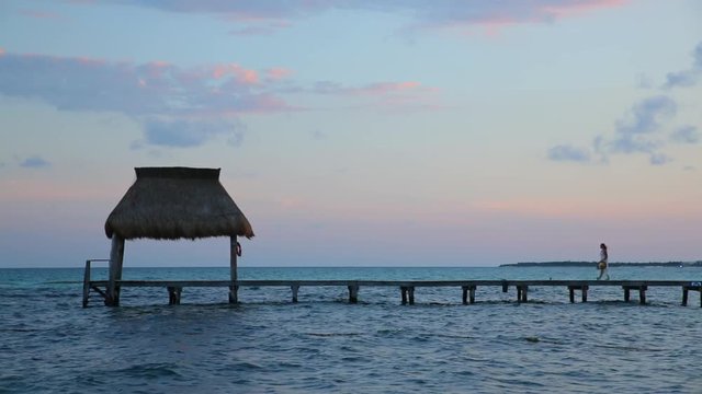Woman walks down pier at dusk