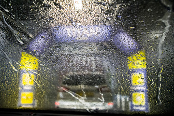 Contactless carwash. Automatic car wash. Drops and streams of water on the car glass.
