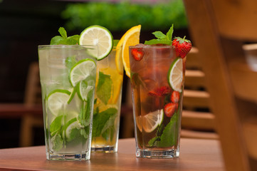 three cold drinks with citrus and strawberries in a glass on the table