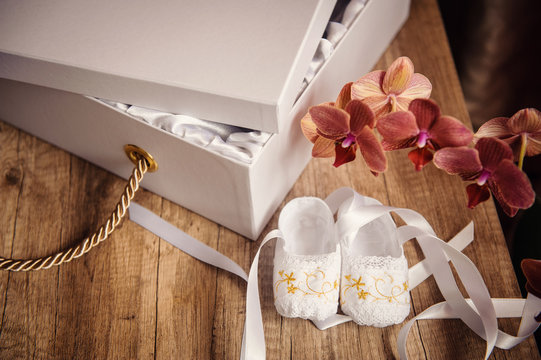 white box with a gift and children shoes on the table - Powered by Adobe