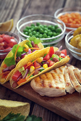 Mexican corn tortilla tacos with vegetables and grilled chicken on wooden background 