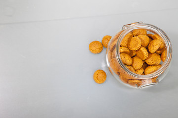Traditional Dutch candy pepernoot in glass jar on grey background
