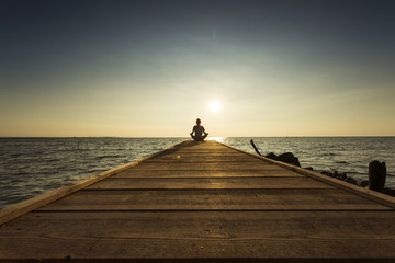 Obraz premium Joyful man meditating on pontoon over a lake at sunrise