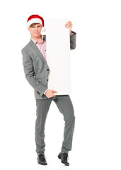 Caucasian man wearing christmas hat for santa. Young businessman in gray suit with blank sign isolated on white background. Successful boy wearing Santa Claus hat - full lenght portrait.