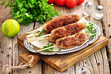 Homemade meat kebabs skewers with dogberry and onion salad on wooden background.