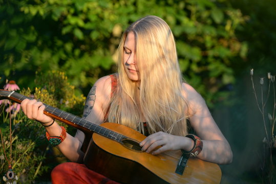 Hippiemädchen mit Gitarre in der Abendsonne