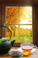 Fototapety  czarna herbata z cytryną jesienią na oknie drewnianej chaty