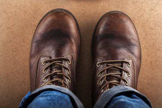 old leather shoes and blue jeans photographed from above