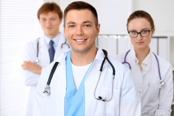 Fototapeta premium Cheerful smiling male doctor with medical staff at the hospital