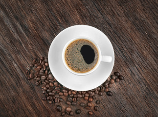 Cup of coffee with beans on wooden background