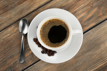 Cup of coffee with beans and spoon on wooden background