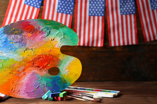 American flags with paint and palette on wooden background