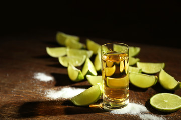Gold tequila shot with lime and salt on wooden table