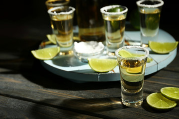 Gold tequila shots with lime and salt on wooden table
