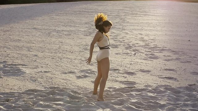Girl doing impromptu dance moves on the sand at sunset
