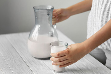 Female hands with milk in jug and glass