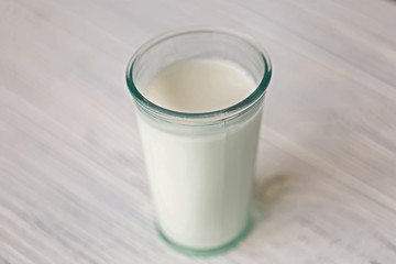 Glass of fresh milk on light blurred background