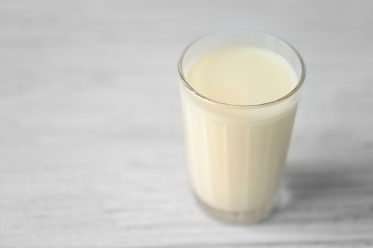 Glass of fresh milk on light blurred background