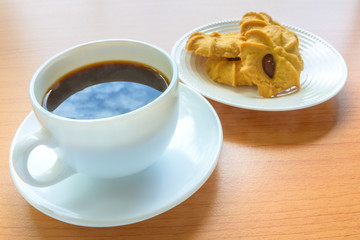 Black coffee and biscuits on wooden table