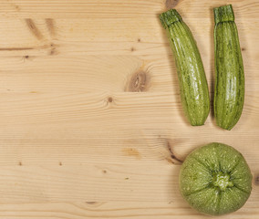Composition of green courgette (zucchini) on a wooden table, two common and one zucchini Di Nizza