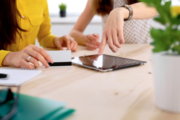 Two business woman or friends are talking and using tablet computer