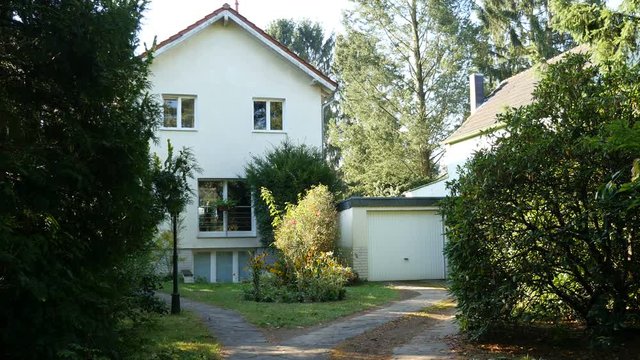 Small residential home, pan from fur tree branches to house and garage, 4K