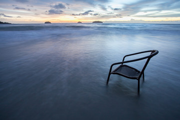 Fototapeta na wymiar Chair in sea at sunset, long time of shutter speed