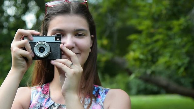 Happy brunette teen girl taking picture with retro camera